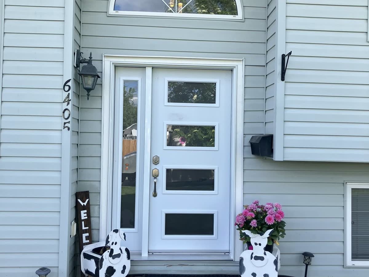New white entry door with sidelight and arched transom — and a pair of cow planters on guard