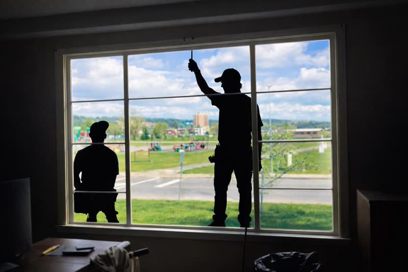 Installers silhouetted against a brand-new picture window overlooking a Prince George park