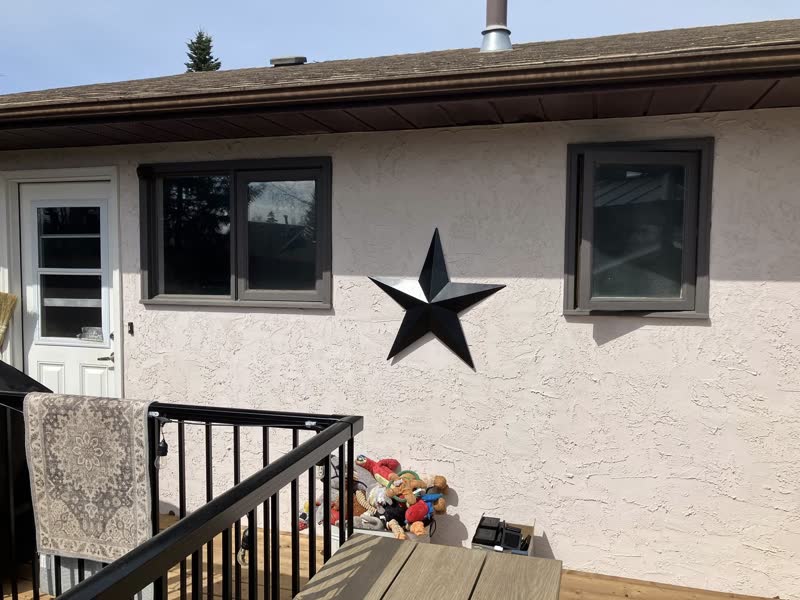 Before the glow-up: dated windows in a stucco wall, lucky star included