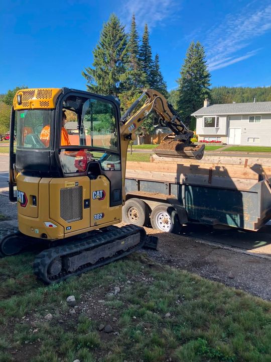 Mini excavator and dump trailer on the job