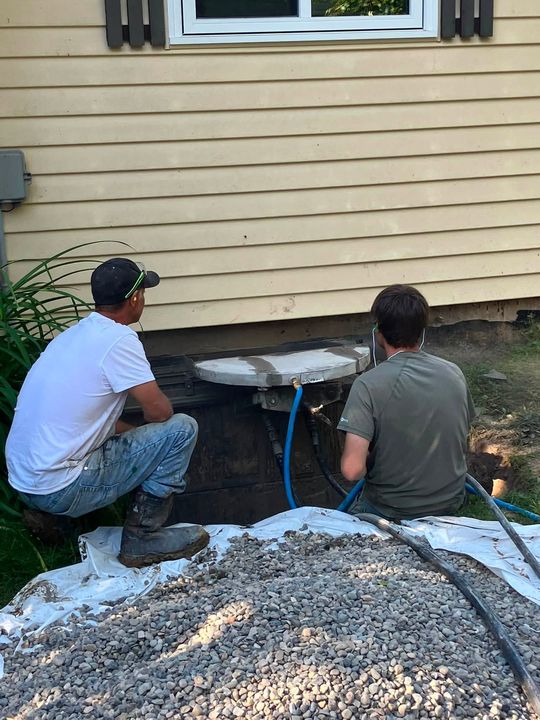 Two crew members cutting the foundation for the egress window