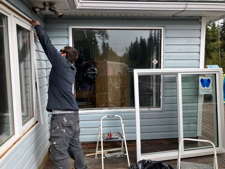 Installer setting a new window, new units waiting on the deck