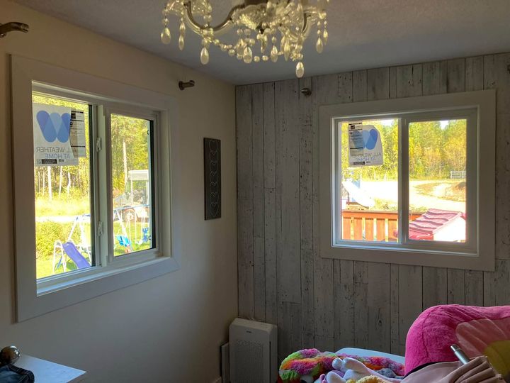 New windows in a bedroom with wood-panel walls