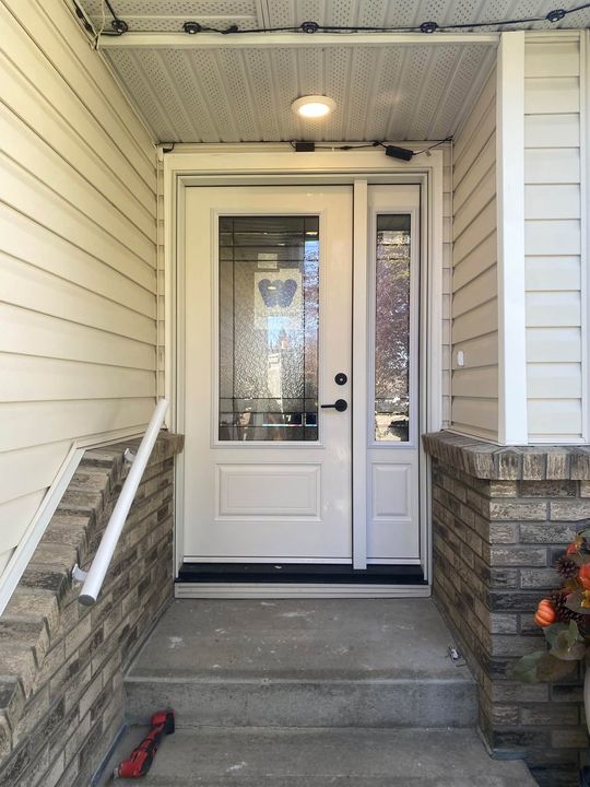 Finished new entry door and sidelite framed by brick in Prince George