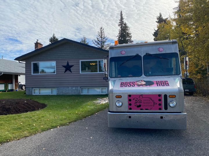 Lipstick work truck parked outside a grey bungalow before the window install