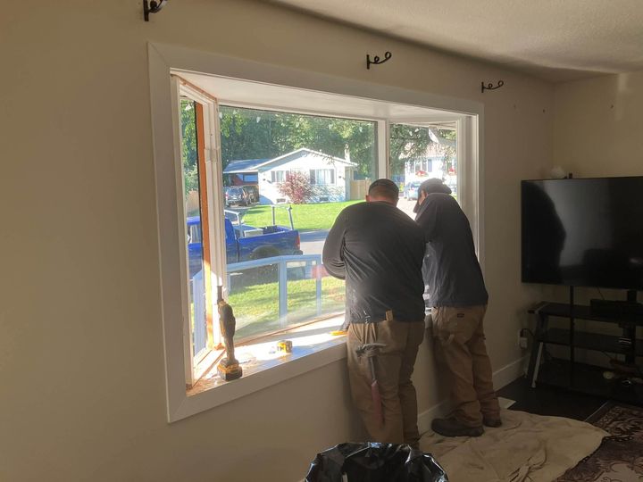 Two installers fitting the new bay window from inside