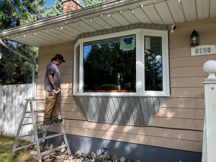 Installer finishing the new front bay window from a ladder