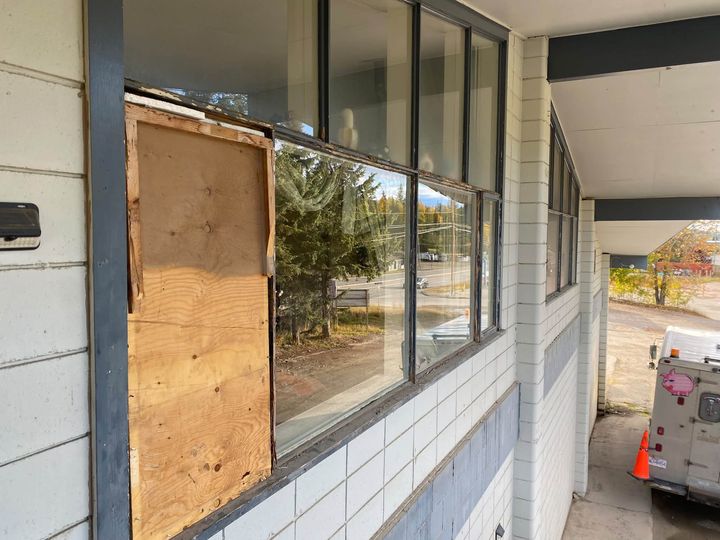 Before: Boarded window opening beside a row of fixed windows on a white brick building