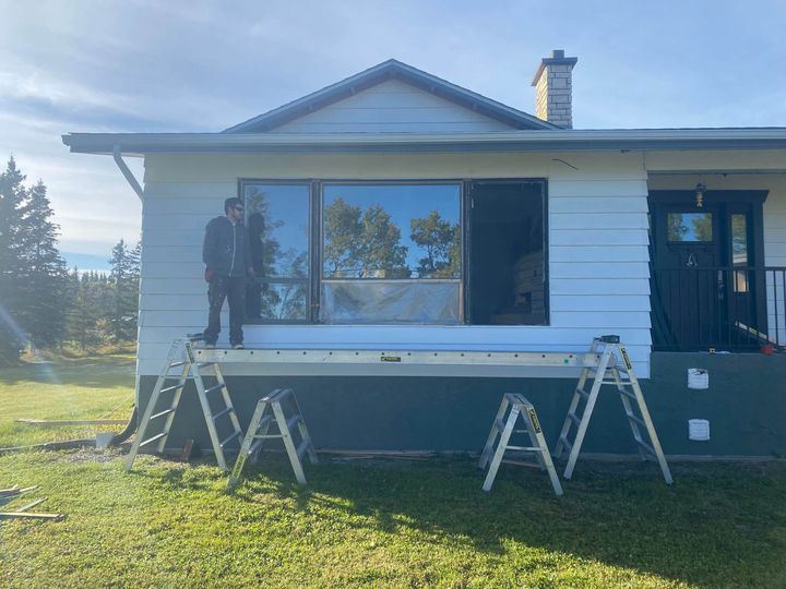 Crew on staging at the front of a white bungalow during the window install